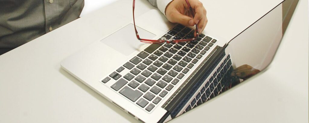 眼鏡を置いたノートパソコンを操作する人物